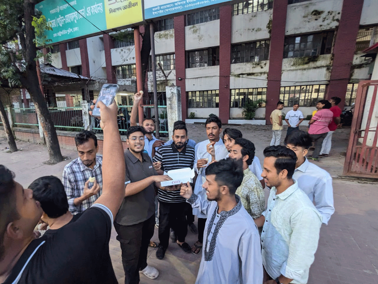 থানার সামনে মিষ্টি বিতরণ করেন কয়েকজন যুবক। ছবি: আজকের পত্রিকা