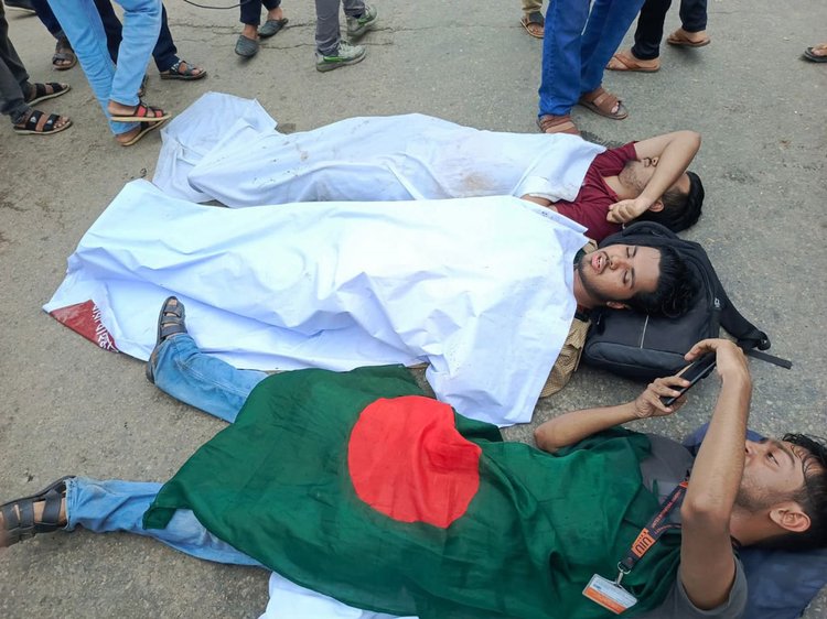 পুলিশের লাঠিপেটার পর শরীরে কাফনের কাপড় জড়িয়ে সড়কে শুয়ে পড়েন তিন শিক্ষার্থী। ছবি: আজকের পত্রিকা