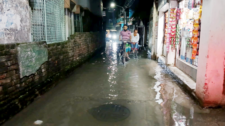 অনেক সময় ড্রেনের ময়লা পানি উপচে ডুবে যায় সড়ক। দুর্গন্ধযুক্ত নোংরা পানি মাড়িয়েই প্রতিদিন স্থানীয়দের চলাচল করতে হয়। গতকাল রাজধানী পূর্ব রামপুরার জামতলার কমিশনার রোডে। ছবি: আজকের পত্রিকা