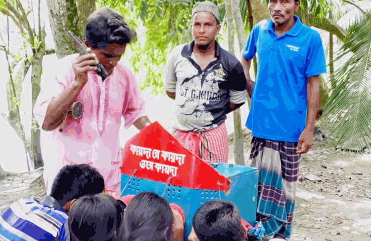 বগলে ডুগডুগি, হাতে করতাল আর কাঁধে বায়োস্কোপের বাক্স নিয়ে রঙে-ঢঙে বিনোদন দিচ্ছেন সর্বানন্দ মধু। ছবি: আজকের পত্রিকা