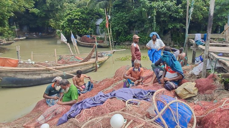 চাঁদপুর সদরের হরিণা মাছঘাট এলাকায় জাল মেরামত করছেন জেলেরা। ছবি: আজকের পত্রিকা।