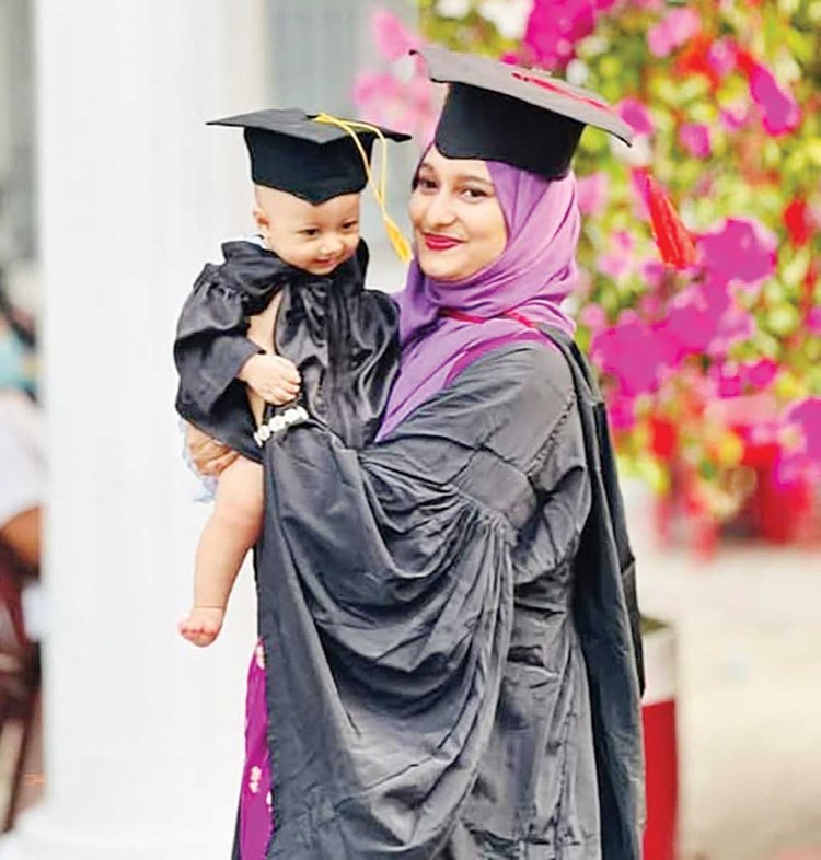 শিশুসন্তানকে নিয়ে সমাবর্তনে অংশ নেওয়া এক মা।	ছবি: আজকের পত্রিকা