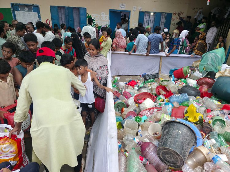 স্থানীয় বাসিন্দারা বিভিন্ন পুনর্ব্যবহারযোগ্য বর্জ্য জমা দিয়ে অস্থায়ী স্টল থেকে নিত্যপণ্য সংগ্রহ করেন। ছবি: আজকের পত্রিকা
