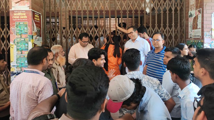 বাধ্য হয়ে কর্মকর্তা-কর্মচারীরা প্রশাসনিক ভবনের একটি কক্ষের জানালা দিয়ে ভর্তির কাগজপত্র নিয়ে কাজ চালান। ছবি: আজকের পত্রিকা