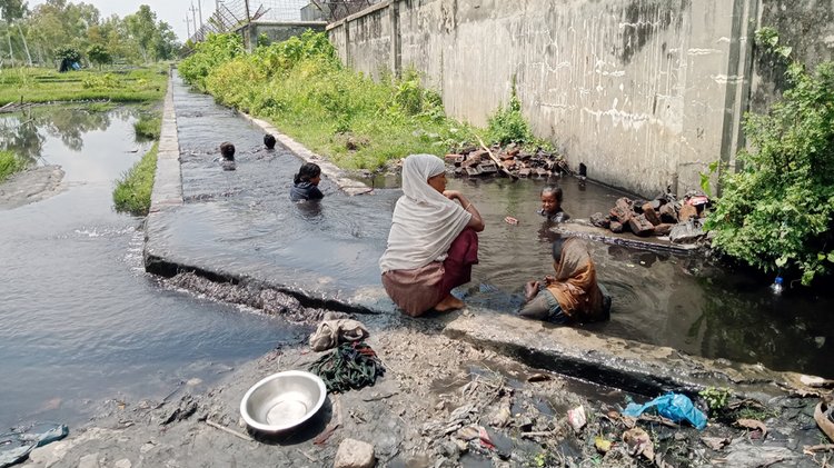 নালার পানিতে নেমে কয়লার ডাস্ট সংগ্রহ করছেন কয়েকজন নারী ও শিশু। ছবি: আজকের পত্রিকা