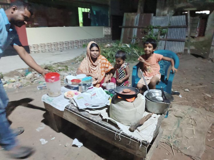 সন্তানদের পাশে বসিয়ে রেখে শকুনি এলাকায় পিঠা বানাচ্ছেন লিপি বেগম। ছবি: আজকের পত্রিকা