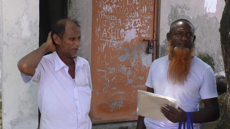 কাগজ হাতে কথা বলছেন অফিসের অলিখিত স্টাফ চান মিয়া এবং অপরজন সেবাপ্রার্থী আলাউদ্দিন। ছবি: আজকের পত্রিকা