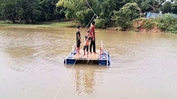 চারটি ড্রাম দিয়ে তৈরি ভাসমান বাহনে দড়ি টেনে পার হতে হচ্ছে স্থানীয় বাসিন্দাদের। ছবি: আজকের পত্রিকা