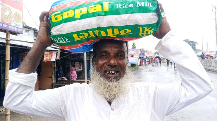 ট্রেন থেকে নামিয়ে দেওয়ায় মাথা পেঁয়াজের বোঝা নিয়ে হাঁটছেন সালথা উপজেলার রসুলপুর গ্রামের বাচ্চু মাতুব্বর। ছবি: আজকের পত্রিকা
