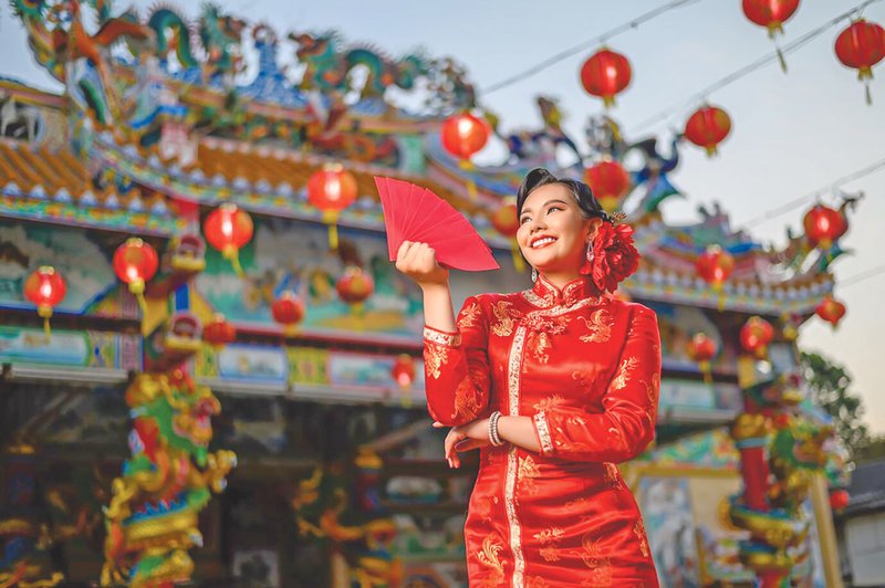 portrait-asian-beautiful-woman-wearing-cheongsam-smiling-holding-red-envelopes-fan-pose-shrine-chinese-new-year_1150-53880