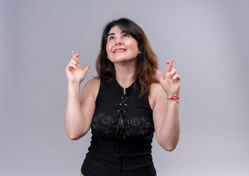 pretty-woman-wearing-black-blouse-dreaming-rejoiced-crossing-her-fingers-gray-background