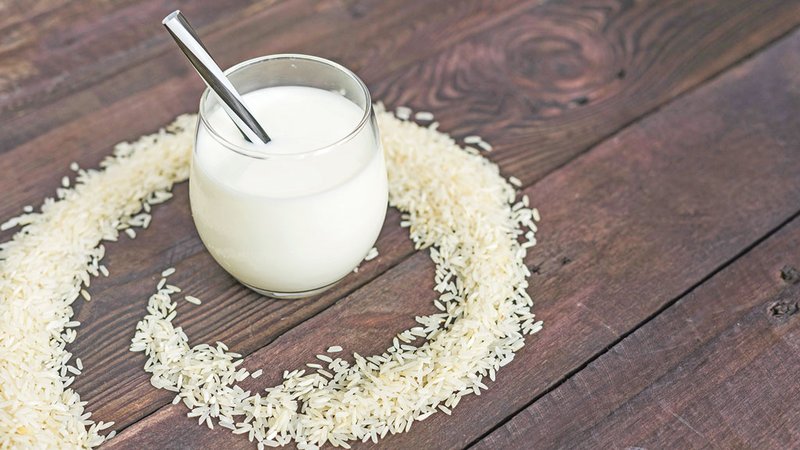 refreshing-rice-milk-glass-with-straw-placed-circular-frame-raw-rice-background