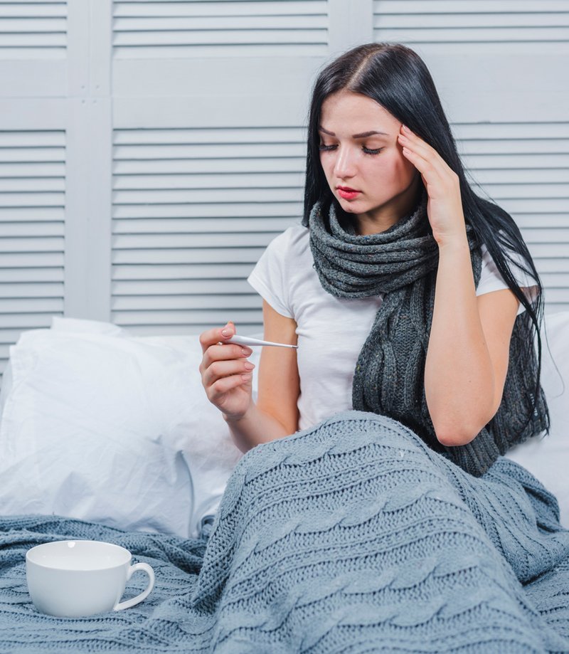 sick-young-woman-sitting-bed-looking-thermometer