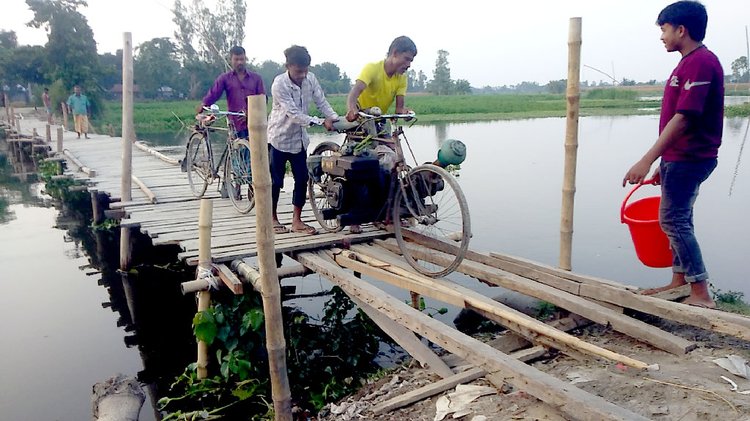 খুব সাবধানে পা ফেলতে হবে। একটু এদিক সেদিক হলে নিশ্চিত দুর্ঘটনা। সুন্দরগঞ্জের তারাপুর ও উলিপুরের বজড়া ও গুনাইগাছ ইউনিয়নের সংযোগ সড়কে বাঁশের সাঁকো। ছবি: আজকের পত্রিকা