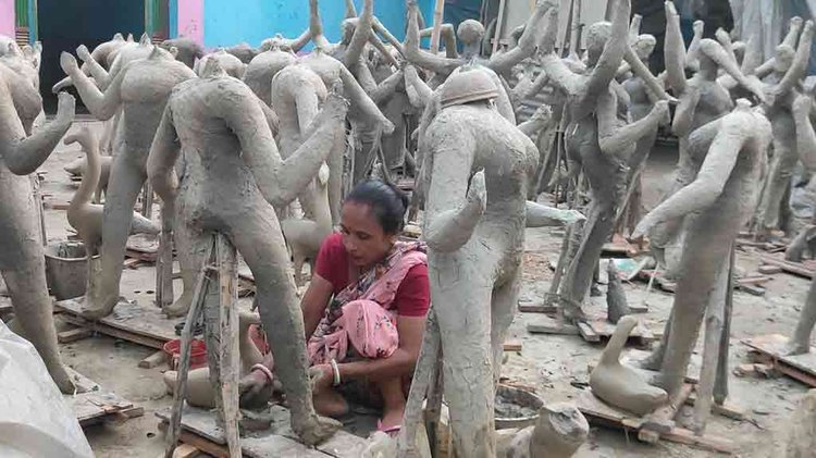 প্রতিমায় মাটির প্রলেপ দিচ্ছেন কারিগর। ছবি: আজকের পত্রিকা