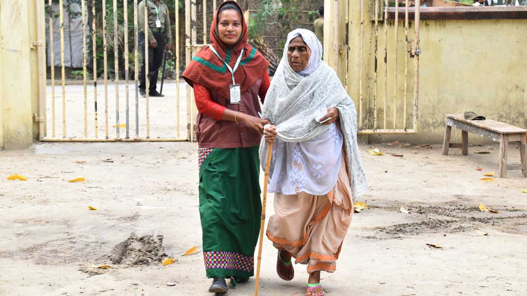 উপজেলা পরিষদ নির্বাচনে ভোট দিতে আসা এক বৃদ্ধাকে সাহায্য করছেন এক নারী আনসার সদস্য। গোদাগাড়ীর ফুলতলার ভাটোপাড়া বালিকা-বালিকা উচ্চ বিদ্যালয় কেন্দ্র থেকে তোলা, রাজশাহী, ৮ মে ২০২৪। ছবি: মিলন শেখ
