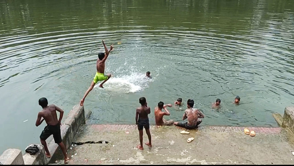 জ্যৈষ্ঠের গরমে ওষ্ঠাগত প্রাণ। এমন হাঁসফাঁস অবস্থায় একটুখানি প্রাণ জুড়াতে একদল শিশু-কিশোরেরা নেমেছে পুকুরে। কাঠফাটা দুপুরে চলছে তাদের দুরন্তপনা। কেউবা পুকুরের বাঁধানো ঘাটের ওপর থেকে লাফিয়ে পড়ছে পানিতে। কেউবা পানিতে সাঁতার কাটছে। সিঙ্গাইর পৌর সদরের উপজেলা পরিষদের পুকুরপাড়, মানিকগঞ্জ, ১৯ মে,২০২৪। ছবি: আব্দুর রাজ্জাক