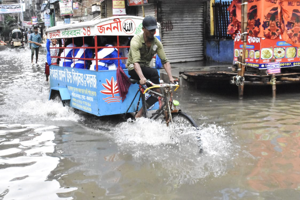 রাস্তায় জমে আছে বৃষ্টির পানি। এর মধ্যে শিক্ষার্থীদের বহনকারী স্কুলভ্যান নিয়ে যাচ্ছেন চালক। কদমতলী একে স্কুল এন্ড কলেজের সামনে। ছবি: মেহেদী হাসান