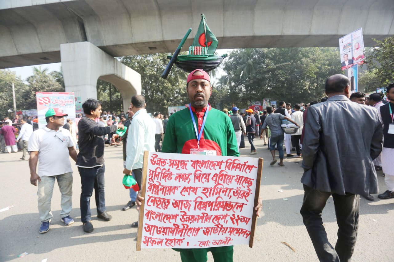 মাথায় নৌকার প্রতিকৃতি ও হাতে ব্যানার নিয়ে সম্মেলন কেন্দ্রে এসেছেন এক সমর্থক। ছবি: হাসান রাজা