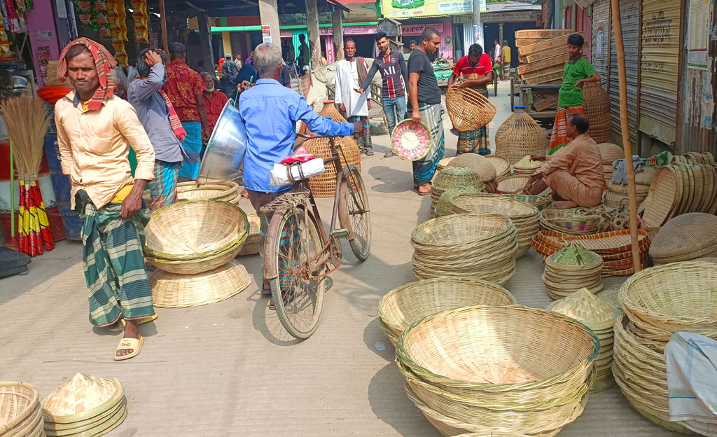 মানিকগঞ্জে গৃহস্থালির কাজে প্লাস্টিক সামগ্রীর চাহিদা বৃদ্ধি পেলেও এখনো বাঁশের তৈরি জিনিসের কদর কমেনি। জেলার সাপ্তাহিক হাট-বাজারগুলোতে পরিমাণে কম হলেও এগুলো বিক্রি হচ্ছে। বিশেষ করে কুলা, ডালা, চাটাই, মাথাইল, পলো, মোড়া, ডুলি, হাতপাখার মতো বাঁশের সামগ্রীর ভালো চাহিদা আছে। সাটুরিয়া হাট থেকে তোলা, ২৬ নভেম্বর ২০২৪। ছবি: আব্দুর রাজ্জাক