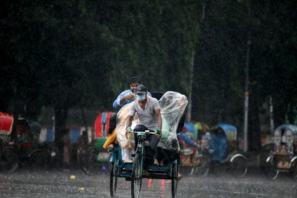 বৃষ্টি মাথায় নিয়ে রিকশায় চড়ে গন্তব্যে যাচ্ছেন কয়েকজন।