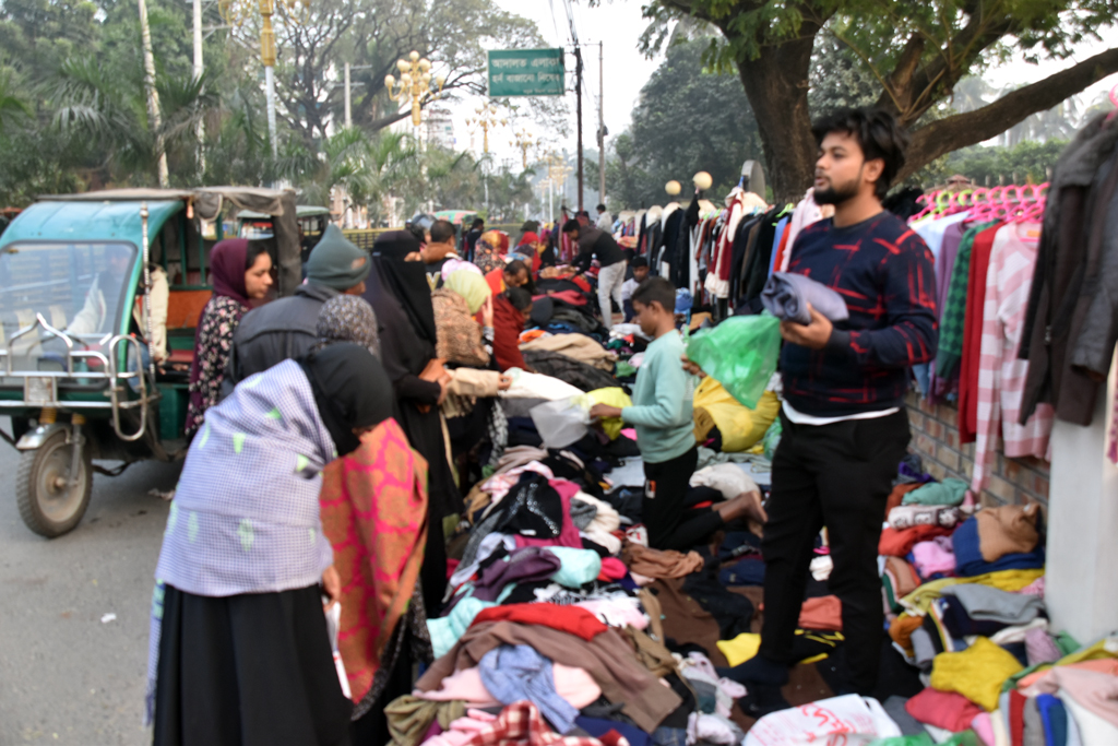 রাজশাহীতে তীব্র শীতে ফুটপাতে গরম কাপড় কেনাবেচার ধুম পড়েছে। ফুটপাতের দোকানগুলো থেকে সোয়েটার, মাফলার, চাদর, হুডিসহ নানা রকম শীতবস্ত্র দেখেশুনে কিনছেন ক্রেতারা। কিছুটা সাশ্রয়ী মূল্যে গরম কাপড় কিনতে নানা শ্রেণি-পেশার মানুষ ফুটপাতের দোকানগুলোয় যাচ্ছেন। নগরীর কোট এলাকা থেকে তোলা। ছবি: মিলন শেখ