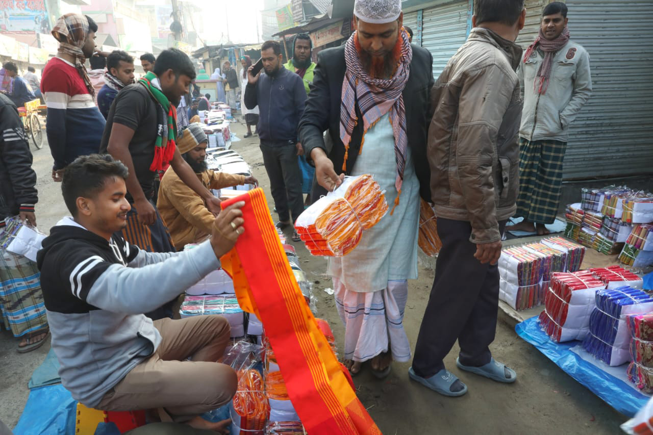 প্রত্যেক সপ্তাহের মঙ্গলবার ও বুধবার বসে কাপড়ের হাট। সেখান থেকে কম দামে শাড়ি কিনে নিয়ে যাচ্ছেন এক ক্রেতা। শাহজাদপুর বিসিক এলাকা, সিরাজগঞ্জ, ৩০ নভেম্বর, ২০২২। ছবি: জাহিদুল ইসলাম