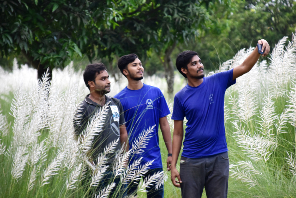 শরতে মাঠ জুড়ে শোভা পাচ্ছে সাদা কাশফুল। স্নিগ্ধ পরিবেশে ক্যামেরায় স্মৃতিটুকু বন্দী করছেন তিন যুবক। রাজশাহী বিশ্ববিদ্যালয়, ৬ সেপ্টেম্বর। ছবি: মিলন শেখ।