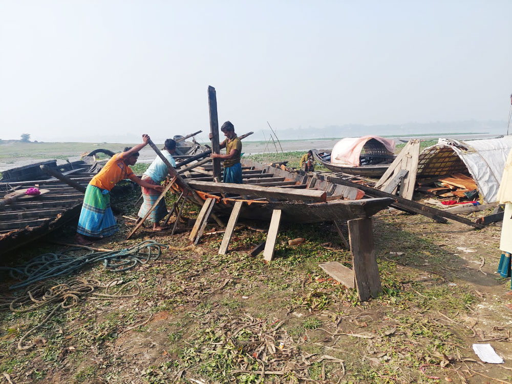 তীব্র শীতে ঘন কুয়াশা ভেদ করে সূর্যের দেখা মিলেছে। এর মধ্যে আরও কয়েকজনকে নিয়ে ভাঙা নৌকা মেরামতে ব্যস্ত এক মাঝি। রায়পুরার চাঁনপুর ইউনিয়নের মাঝেরচর এলাকা থেকে সম্প্রতি তোলা, নরসিংদী, ২৭ জানুয়ারি ২০২৪। ছবি: হারুনূর রশিদ