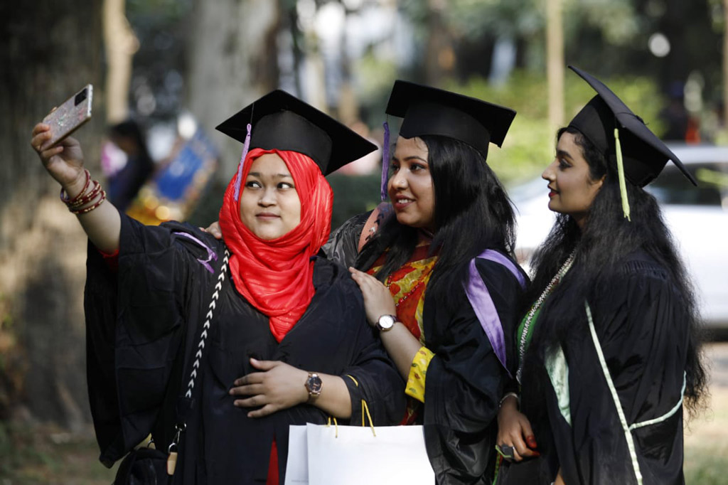 সমাবর্তন নিতে আসা তিন বান্ধবী গাউন ও টুপি পড়ে নিজেদের বিশেষ সময়ের ছবি ধারণ করছেন।