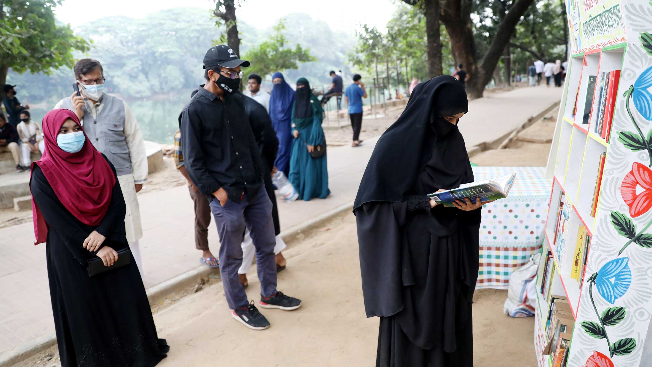 মানুষকে বই পড়তে উদ্বুদ্ধ করতে, সেই সঙ্গে যেখানে-সেখানে ফেলে দেওয়া প্লাস্টিকের সঠিক স্থানে ফেলার বা তা পুনরায় ব্যবহারের উদ্দেশ্য নিয়ে ঢাকার ধানমন্ডির রবীন্দ্র সরোবরে প্লাস্টিকের বর্জ্য বিনিময় বইয়ের উদ্যোগ নিয়েছেন ভলান্টিয়ার অর্গানাইজেশন ‘পাশে আছি ইনিশিয়েটিভ’। ধানমন্ডি, ঢাকা। ৪ ডিসেম্বর ২০২১। ছবি:  হাসান রাজা