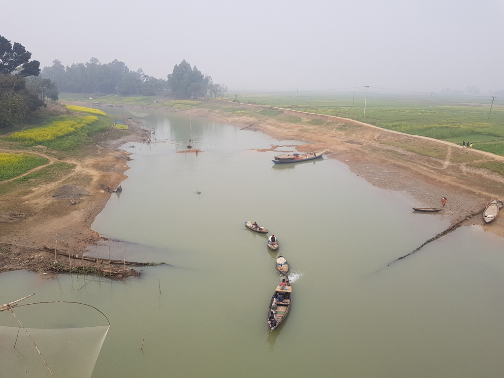 গুমানী নদীর পানি প্রায় শুকিয়ে গেছে। সেখানে দেশীয় প্রজাতির ছোট-বড় মাছ ধরা পড়ছে। জেলেদের ডিঙি নৌকা নিয়ে মাছ শিকারে যেতে দেখা যাচ্ছে। চাটমোহরের নিমাইচড়া এলাকার গুমানী নদী, পাবনা, ২৫ জানুয়ারি ২০২৪। ছবি: শুভাশীষ ভট্টাচার্য্য তুষার
