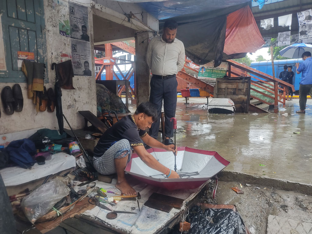 ঘূর্ণিঝড় রিমালের প্রভাবে বাতাসের সঙ্গে শুরু হয়েছে বৃষ্টি। এ জন্য বেড়েছে ছাতার চাহিদা। পুরোনো নষ্ট ছাতা ঠিক করতে মানুষ ভিড় জমাচ্ছেন ছাতা মেরামতকারী দোকানে।  কামারখন্দ উপজেলার জামতৈল রেলওয়ে স্টেশন এলাকা থেকে তোলা, সিরাজগঞ্জ, ২৭ মে ২০২৪। ছবি: আব্দুল্লাহ আল মারুফ