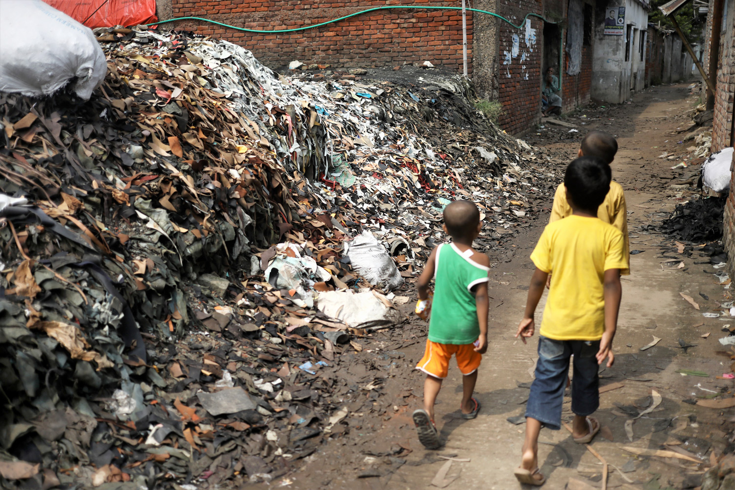 চামড়ার উচ্ছিষ্ট অংশ রাস্তার পাশেই ফেলে রাখা হয়েছে। তারই পাশ দিয়ে হাঁটাচলা করছে ওই এলাকার কিছু বাচ্চা।