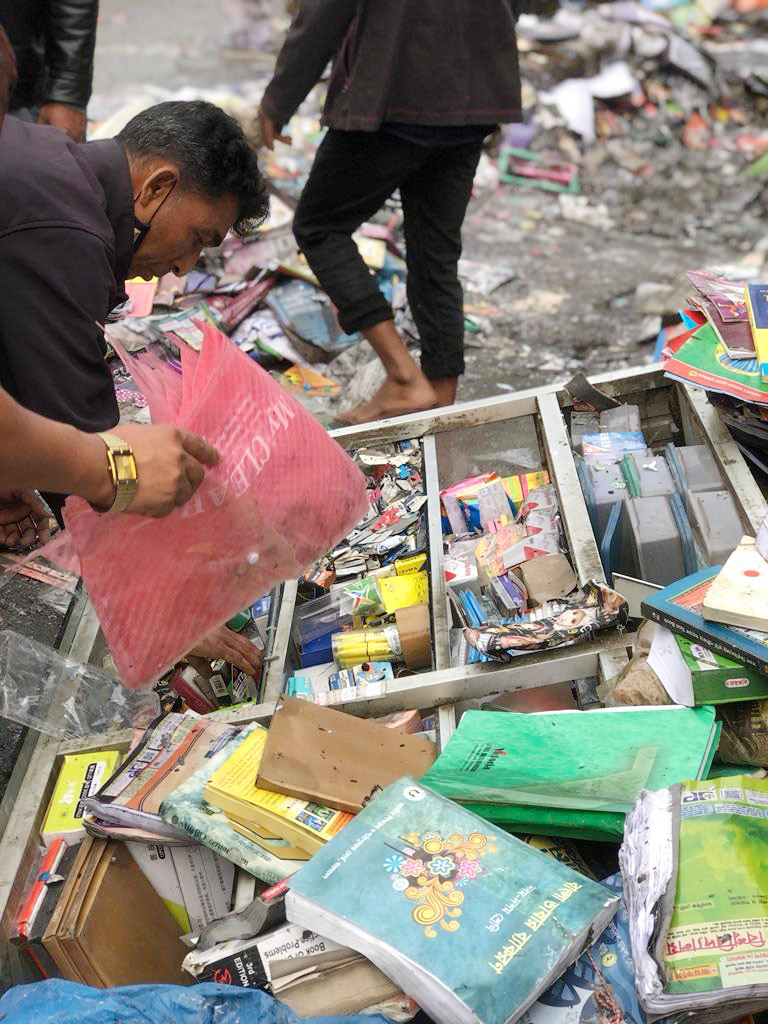 আগুনে পুড়ে যাওয়া দোকানে বই খুঁজছেন এক দোকানি 