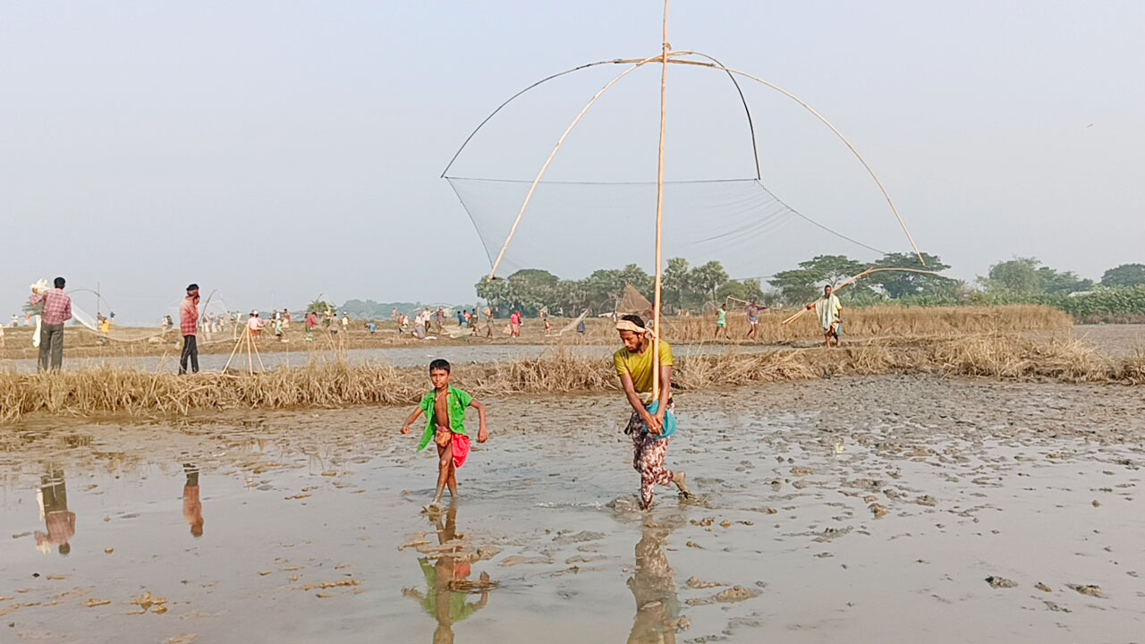শিশির ভেজা সকালে কাঁদা মাখা পথ মাড়িয়ে, ছিপ জাল কাঁধে নিয়ে বিলের পানিতে মাছ ধরতে যাচ্ছেন মাছ শিকারি। ত্রিশাল উপজেলার মঠবাড়ী ইউনিয়নের খাগাটি গ্রামের কেচুরি বিল, ময়মনসিংহ, ১৯ নভেম্বর ২০২৩। ছবি: সাইফুল আলম তুহিন