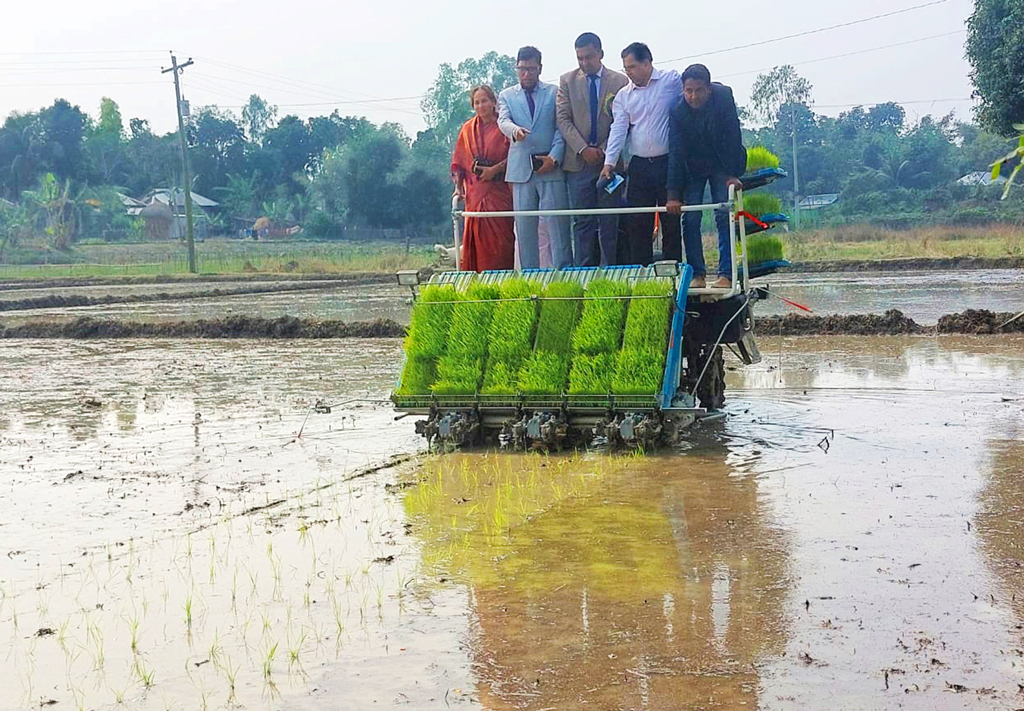 আধুনিক প্রযুক্তি রাইস ট্রান্সপ্লান্টারের মাধ্যমে বোরো ধানের চারা রোপণ করছেন কৃষকেরা। ঘিওর উপজেলায় এ বছরই প্রথম এ পদ্ধতিতে ধান চাষের আওতায় আনা হয়েছে কিছু কৃষককে। একটি ফসলের মাঠে কৃষি কর্মকর্তারা এ কার্যক্রমের উদ্বোধন করেন। ঘিওর ইউনিয়নের মাইলাগী গ্রাম, মানিকগঞ্জ, ২০ ফেব্রুয়ারি ২০২৪। ছবি: আব্দুর রাজ্জাক