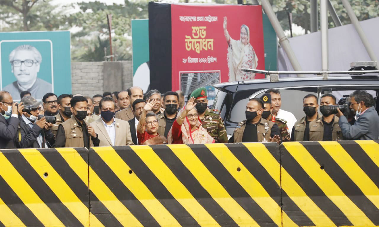 মেট্রোরেলে চড়ে মাত্র ১০ মিনিটে দিয়াবাড়ি থেকে আগারগাঁওয়ে পৌঁছান প্রধানমন্ত্রী। আগারগাঁও স্টেশনে নেমে শেখ রেহানাসহ অন্যদের সঙ্গে দাঁড়িয়ে জনতার উদ্দেশে হাত নাড়েন তিনি। ছবি: মেহেদি হাসান