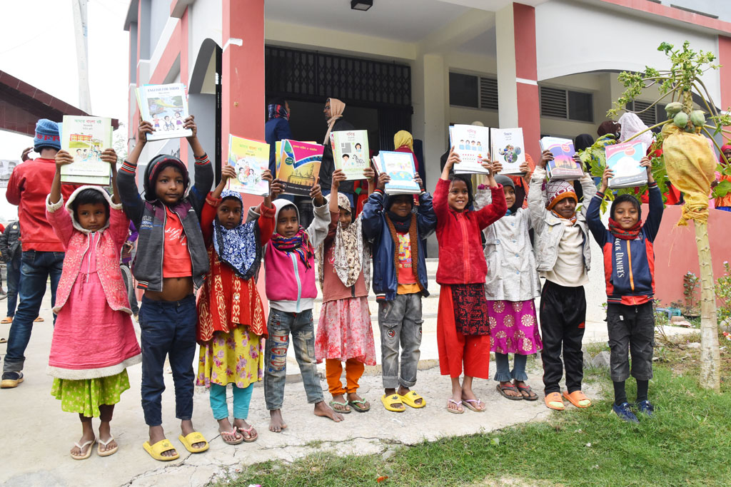 বছরের প্রথম দিন নতুন বই হাতে পেয়েছে শিক্ষার্থীরা। সেই খুশিতে বই উঁচু করে ধরে ছবি তোলার জন্য দাঁড়িয়েছ হাসি-মুখে। গোদাগাড়ী উপজেলা রিশিকুল ইউনিয়নের চব্বিশ নগর ওয়াক্ফ দাখিল মাদ্রাসা, রাজশাহী, ১ জানুয়ারি ২০২৪। ছবি: মিলন শেখ
