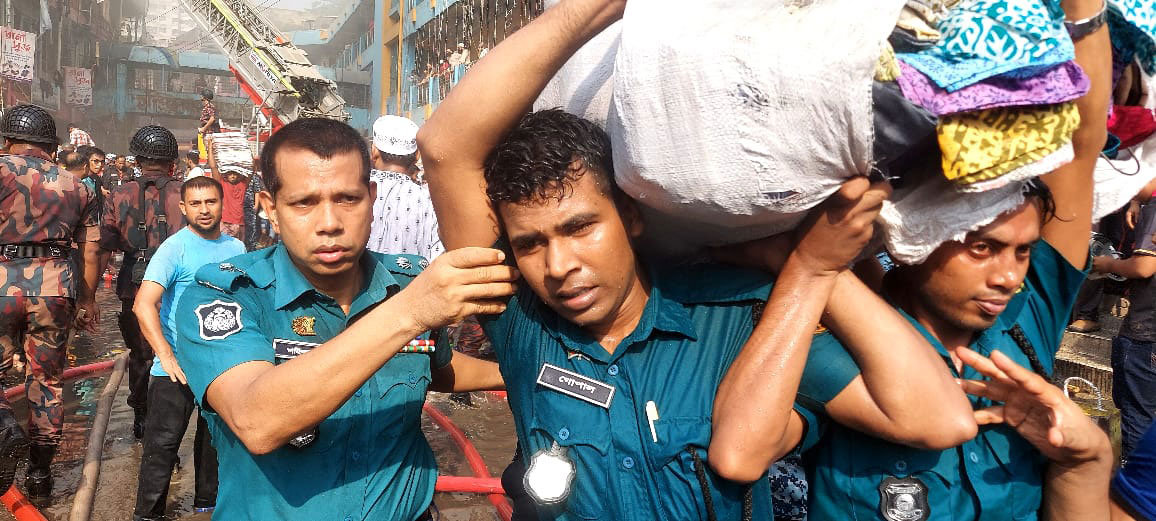 কাঁধে নিয়ে ব্যবসায়ীদের মালামাল নিরাপদ স্থানে সরিয়ে নিচ্ছেন পুলিশ সদস্যরা