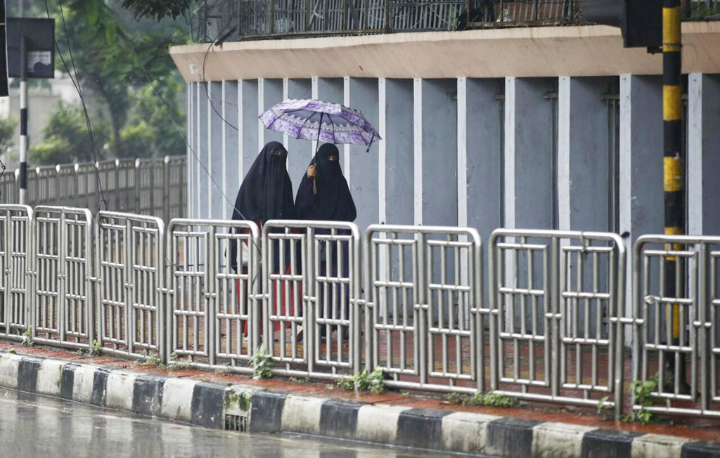 বৃষ্টিতে ছাতা মাথায় বেরিয়েছেন দুই নারী। 