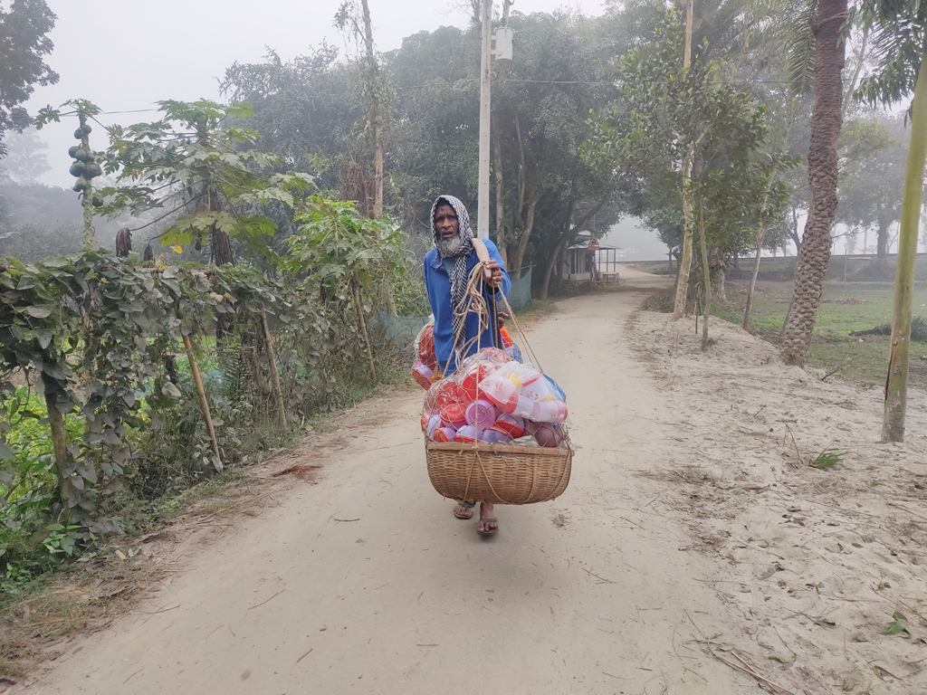 নিত্যপ্রয়োজনীয় প্লাস্টিকের পণ্য বিক্রির জন্য বেরিয়ে পড়েছেন আছের নামের এক বৃদ্ধ। কামারখন্দ, সিরাজগঞ্জ, ৪ জানুয়ারি ২০২৩। ছবি: আব্দুল্লাহ আল মারুফ।