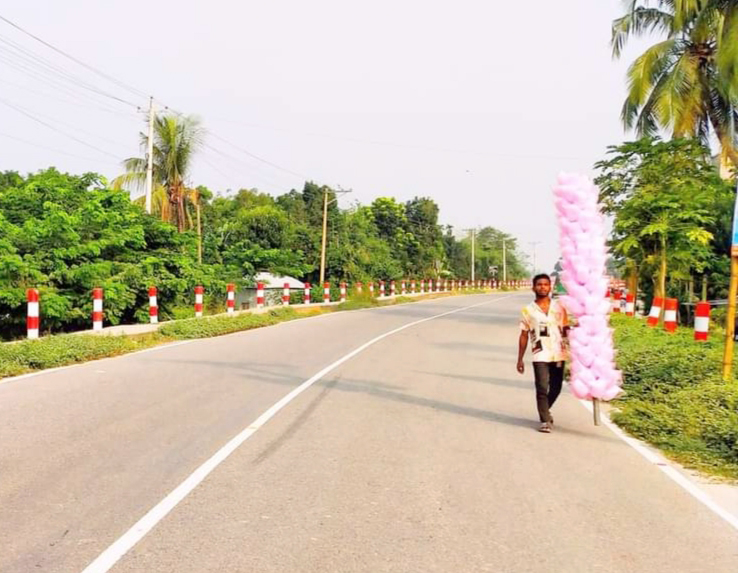 হাওয়ার সঙ্গে বিলীন হয়ে যায় বলেই এর নাম ‘হাওয়াই মিঠাই’। গ্রামের এই মিঠাই এখন কিছুটা আধুনিক হয়ে শহরেও পৌঁছে গেছে। শিশুদের কাছে জনপ্রিয় এই খাবার দেখলে অনেক সময় বড়রাও লোভ সামলাতে পারেন না। এক বিক্রেতাকে হাওয়াই মিঠাই নিয়ে রাস্তা দিয়ে হেঁটে যেতে দেখা যাচ্ছে। ঘিওর-টাঙ্গাইল আঞ্চলিক সড়কের ঘিওর নতুন ব্রিজ এলাকা, মানিকগঞ্জ, ১৭ অক্টোবর ২০২৩। ছবি: আব্দুর রাজ্জাক