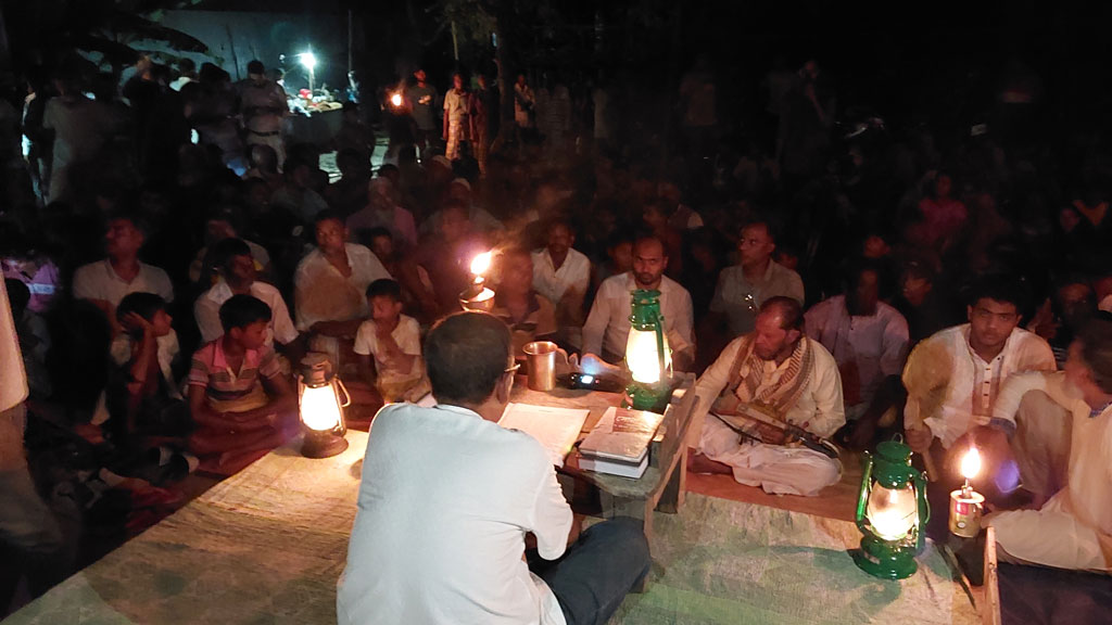 পুঁথি পাঠের আসরে পুঁথি পাঠ করছেন নাট্যজন আসাদুজ্জামান দুলাল। সামনে মন্ত্রমুগ্ধ দর্শক। বৃহস্পতিবার রাতে পাবনার চাটমোহর উপজেলার সোনাহারপাড়া গ্রামে। ছবি: আজকের পত্রিকা