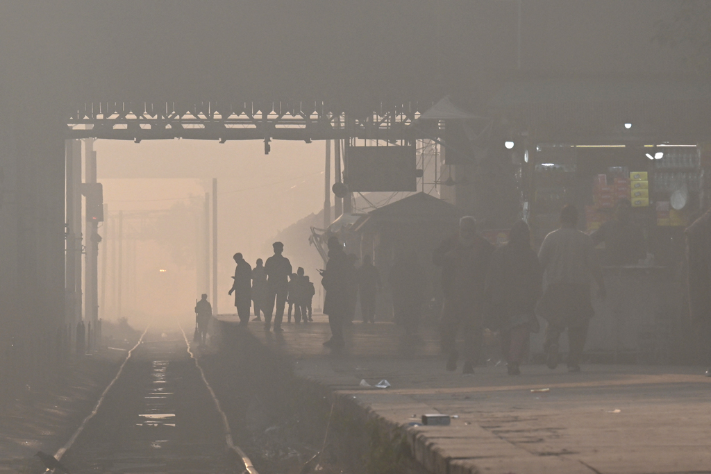 তীব্র বায়ুদূষণ ও কুয়াশা এক হয়ে পরিণত হয়েছে ধোঁয়াশায়। রেলস্টেশনে ট্রেন আসার অপেক্ষা করছেন যাত্রীরা। পাকিস্তানের লাহোর থেকে তোলা। ছবি: আরিফ আলী, এএফপি