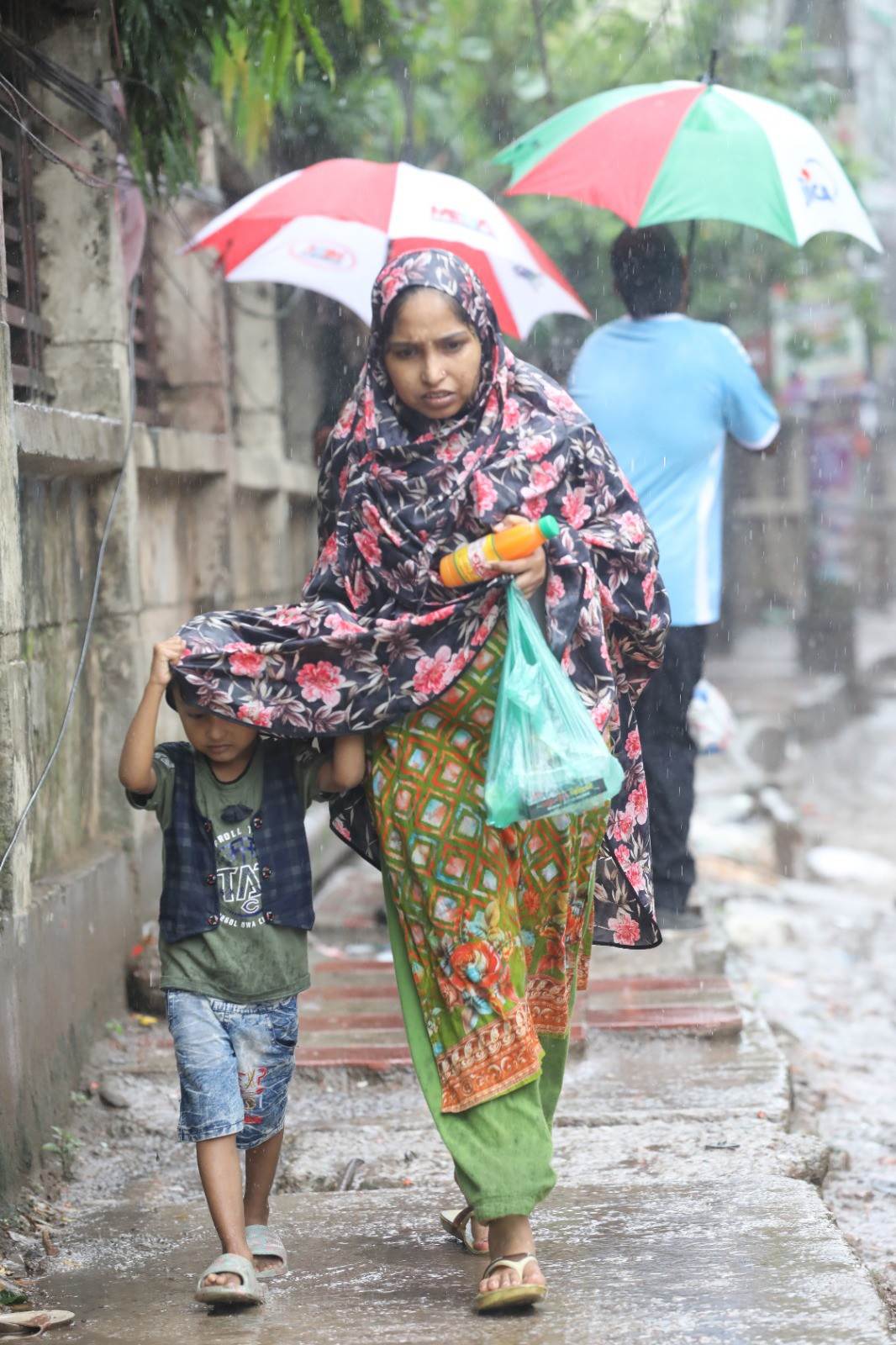 সকাল থেকেই বৃষ্টি হচ্ছে। কখনো গুঁড়ি গুঁড়ি, কখনোবা মুষলধারে। ছাতা না থাকায় এক শিশু ও নারীকে বৃষ্টিতে ভিজতে দেখা যায়। মুগদা এলাকায় তোলা। ছবি: মেহেদী হাসান