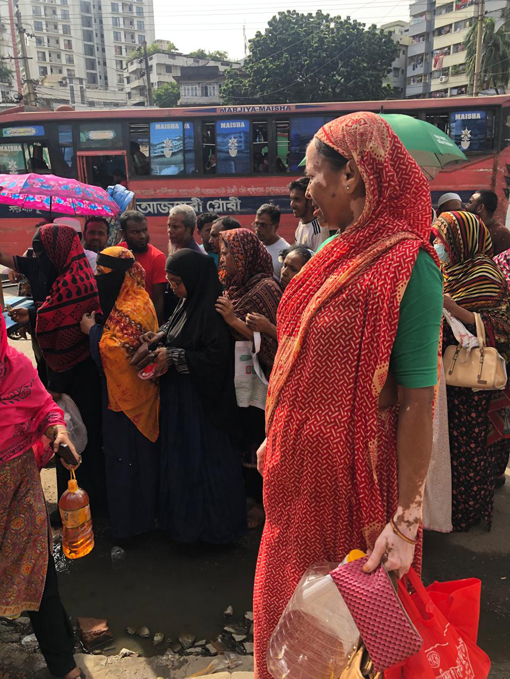 দীর্ঘক্ষণ রোদে দাঁড়িয়ে অপেক্ষার পর শান্তিনগরে ট্রাক থেকে টিসিবির তেল, চিনি ও ডাল কিনেন আমেনা খাতুন। ছবি: আজকের পত্রিকা