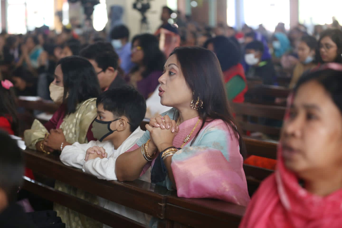 ধর্মযাজকদের সঙ্গে প্রার্থনায় মগ্ন এক নারী। তেজগাঁও চার্জ, ঢাকা। ছবি: আজকের পত্রিকা