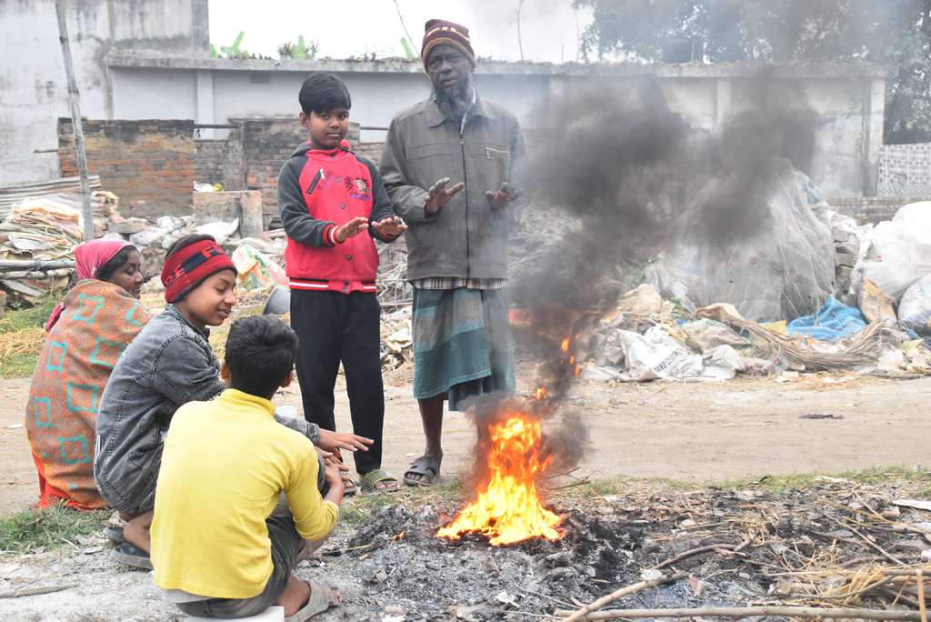 শীতের সকালে উষ্ণতার খোঁজে আগুনের দ্বারস্থ হয়েছেন কয়েকজন খেটে খাওয়া মানুষ। সঙ্গে যোগ দিয়েছে কয়েকজন ছিন্নমূল শিশু-কিশোর। নগরীর আম চত্বর এলাকা থেকে তোলা, রাজশাহী, ২৫ জানুয়ারি ২০২৫। ছবি: মিলন শেখ