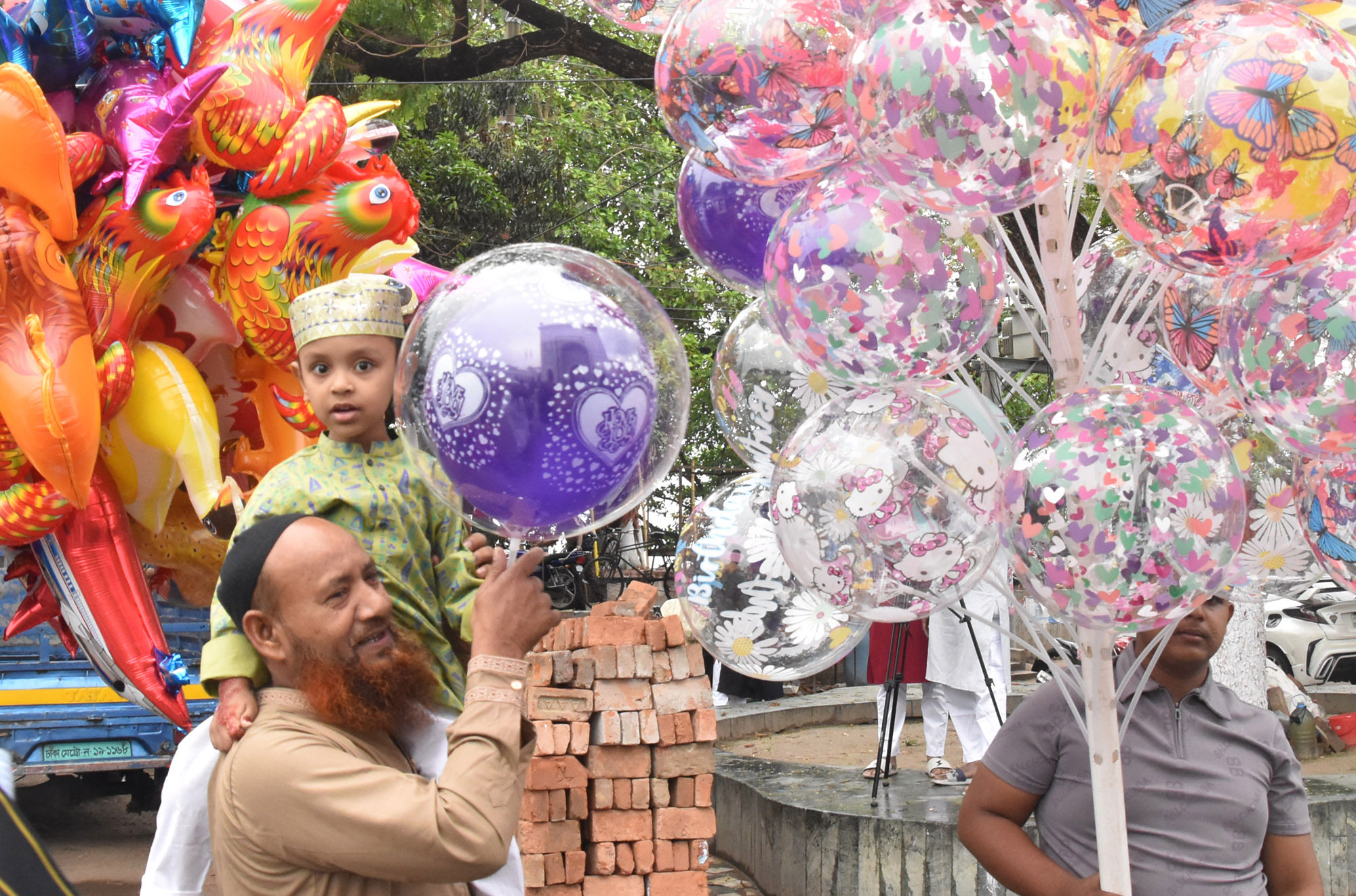 ঈদের নামাজ শেষে শিশুকে রঙিন বেলুন কিনে দেন স্বজন। আজ রাজশাহী নগরীর দরগাপাড়া এলাকা থেকে তোলা। ছবি: মিলন শেখ